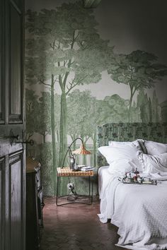 a bed sitting in a bedroom next to a forest wallpaper