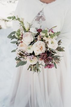 a bride holding her bouquet in the snow