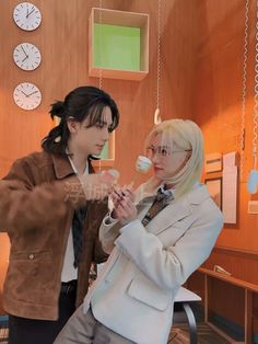 two people standing next to each other with toothbrushes in their hands and clock on the wall behind them