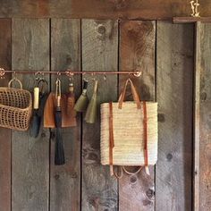 several purses hanging on a wooden wall with hooks and umbrellas attached to them