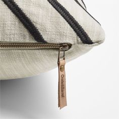 a black and white striped pillow with a zipper on the front, along with a leather tag