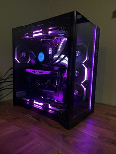 a purple and black computer case sitting on top of a wooden table next to a plant