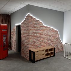 an empty room with a brick wall and red phone booth in the corner, next to a white crib