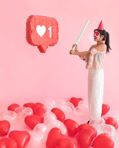 a woman holding a baseball bat standing in front of red heart balloons with i love you written on it