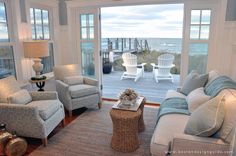 a living room filled with lots of furniture next to a large glass door that leads out to the beach