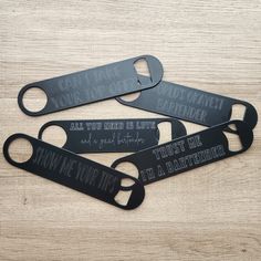 four black bottle openers with words on them