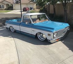 a blue and white truck parked on the side of a road next to a house