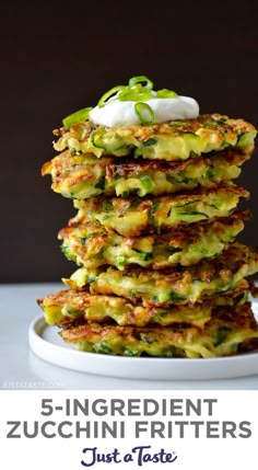 a stack of zucchini fritters with sour cream on top