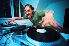 a man with headphones on and pointing at a turntable in front of him