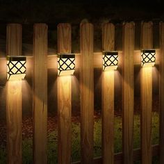 four lights are on the side of a wooden fence