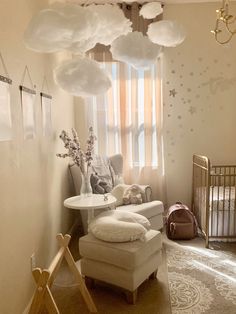 a baby's room with clouds hanging from the ceiling and a crib in the corner