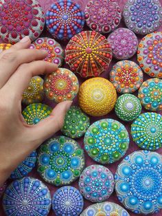 a person's hand on top of some colorful rocks and balls in the shape of flowers