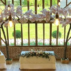 the table is set up with flowers and candles on it in front of an open window