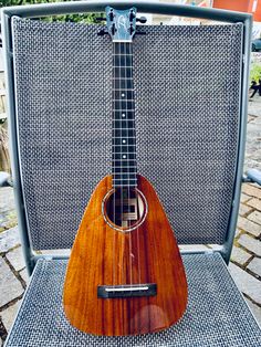 a ukulele sitting on top of a chair in front of a metal screen