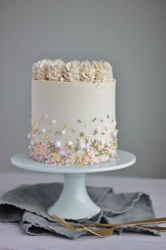 a white cake topped with sprinkles and frosting on top of a table