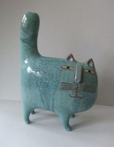 a ceramic cat figurine sitting on top of a white table next to a wall