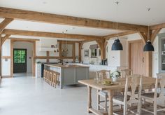 a large open kitchen and dining room with wood beams on the ceiling, white tile floor