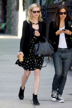 two women walking down the street with cell phones