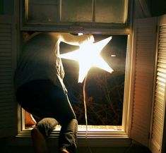 a person standing in front of a window with a light shining on it's side