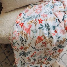 a dog laying on top of a bed covered in a flowered blanket next to pillows