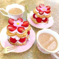 two desserts on pink plates with strawberries and flowers next to a cup of coffee