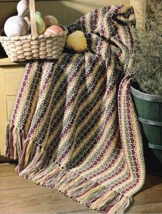 a basket with some fruit and vegetables sitting on top of a table next to a blanket