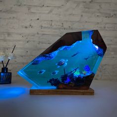 an aquarium with blue lights in front of a white brick wall and two vases filled with flowers