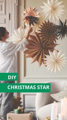 a woman is decorating a christmas star on the wall with candles and presents in front of her