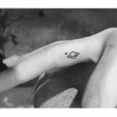 a small saturn tattoo on the left hand is shown in this black and white photo