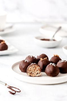 some chocolates are on a white plate with spoons and bowls in the background