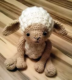 a crocheted sheep sitting on top of a wooden floor