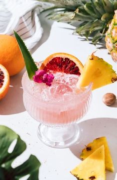 a pink cocktail garnished with fresh fruit and pineapple