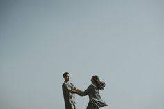 two people standing on top of a grass covered field