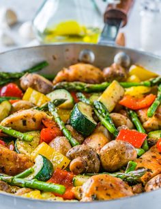 a pan filled with chicken, asparagus, and peppers on top of a table