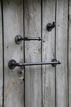 two black handles on a wooden door with wood planks in the backround