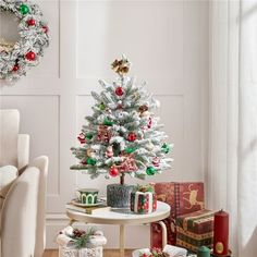 a small christmas tree sitting on top of a white table next to presents and gifts