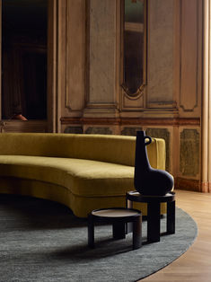 a yellow couch sitting on top of a wooden floor next to a black chair and table