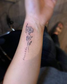 a woman's arm with a flower tattoo on the left side of her wrist