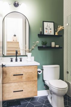 a white toilet sitting next to a wooden sink vanity in a bathroom under a mirror