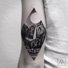 a black and white photo of a mountain with a half moon tattoo on the arm