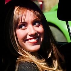 a woman sitting in the back seat of a car with her eyes open and smiling