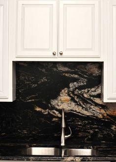 a kitchen with marble counter tops and white cabinets