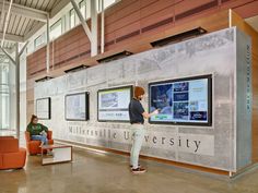 two people are standing in front of a large poster with information about the university on it