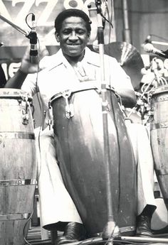 a black and white photo of a man sitting in front of drums