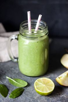 a green smoothie in a mason jar with two straws