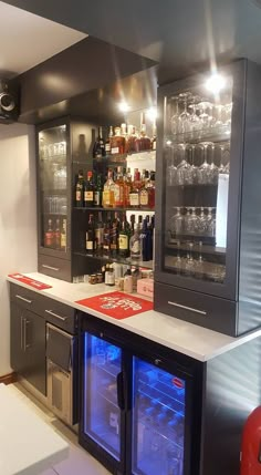 a bar with wine glasses and liquor bottles on the shelves in a home kitchen area