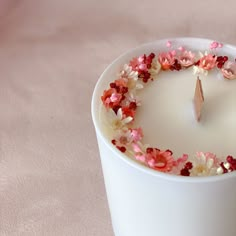 a white candle with pink and red flowers on it