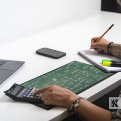 a woman sitting at a desk with a calculator, notebook and pen in front of her