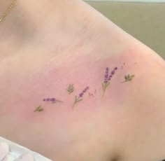 a woman's stomach with small purple flowers on the left side of her breast