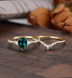 two gold rings with green and white stones on them sitting on a wooden table next to a baby